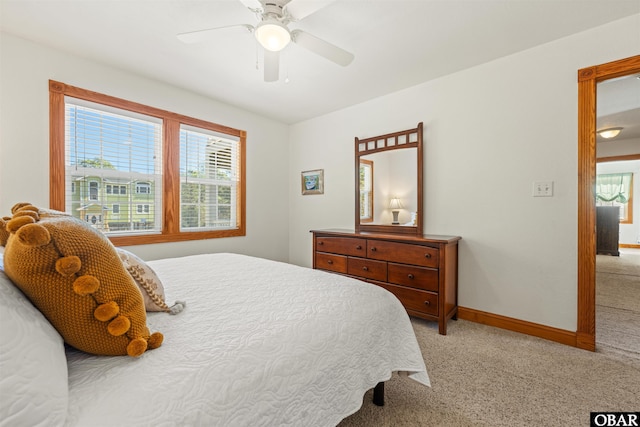 bedroom with light carpet, ceiling fan, multiple windows, and baseboards