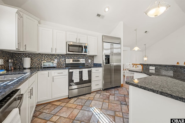 kitchen featuring stainless steel appliances, stone finish flooring, white cabinetry, and decorative light fixtures