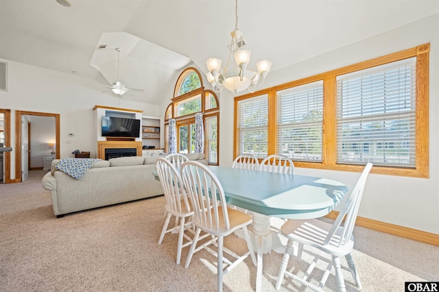 dining area featuring a fireplace, light carpet, vaulted ceiling, baseboards, and ceiling fan with notable chandelier