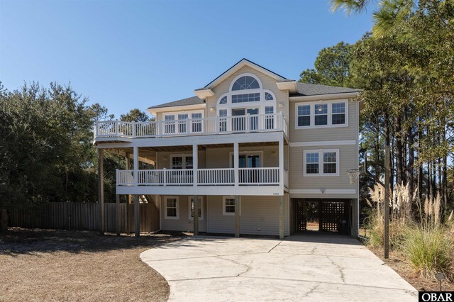 raised beach house with driveway, a balcony, and fence