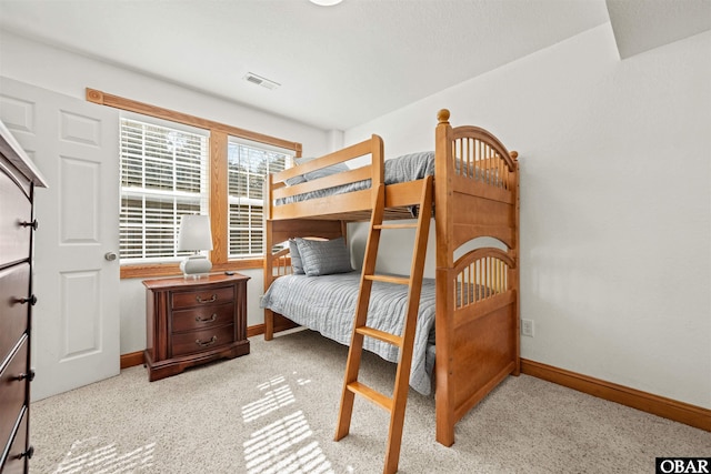 bedroom featuring visible vents, light colored carpet, and baseboards