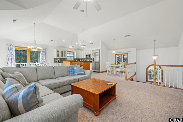 living area with lofted ceiling, ceiling fan with notable chandelier, light carpet, and visible vents