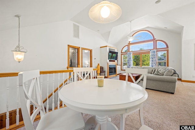 carpeted dining area featuring high vaulted ceiling, a fireplace, a ceiling fan, visible vents, and baseboards