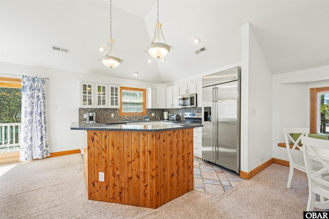 kitchen with stainless steel appliances, dark countertops, white cabinetry, and light colored carpet