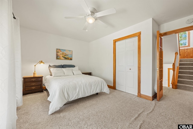 bedroom featuring a ceiling fan, a closet, light carpet, and baseboards