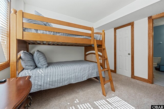 bedroom with carpet floors, connected bathroom, and baseboards