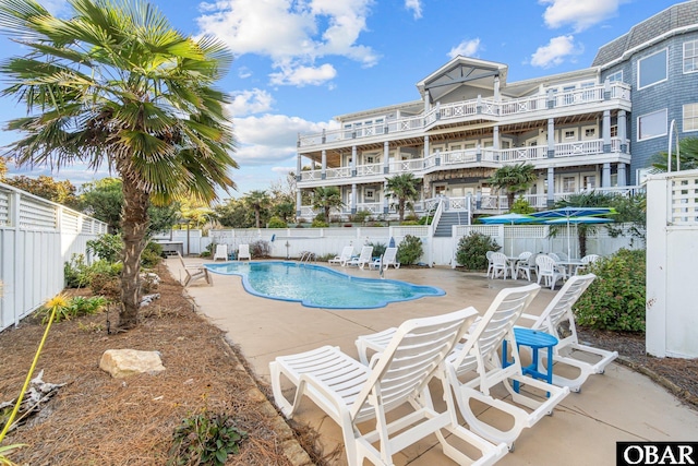 community pool with a patio area and a fenced backyard