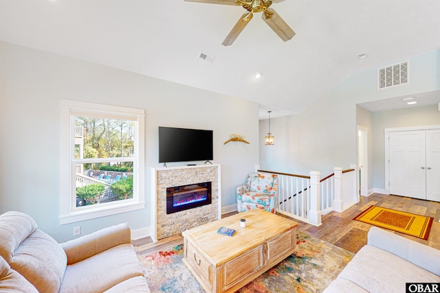 living area with vaulted ceiling, wood finished floors, visible vents, and baseboards