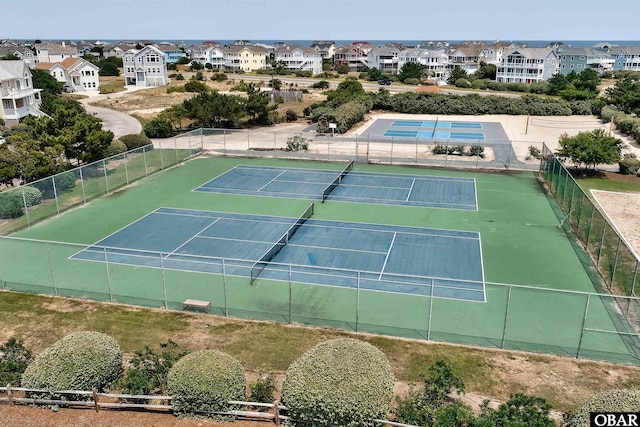 view of tennis court featuring fence and a residential view