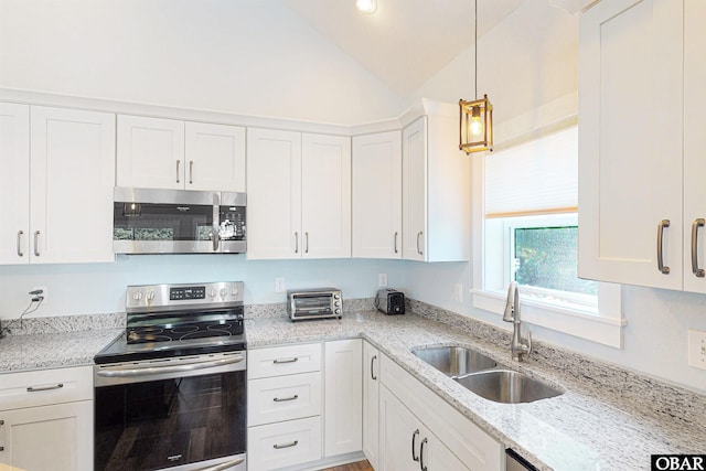 kitchen featuring decorative light fixtures, stainless steel appliances, lofted ceiling, white cabinetry, and a sink