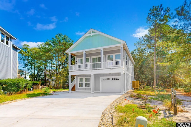 raised beach house with driveway, a garage, and board and batten siding