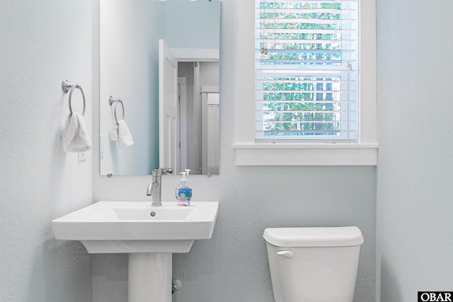 bathroom featuring a textured wall and toilet