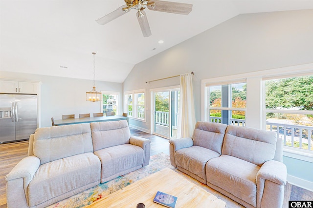 living room with lofted ceiling, light wood-style flooring, ceiling fan with notable chandelier, visible vents, and baseboards