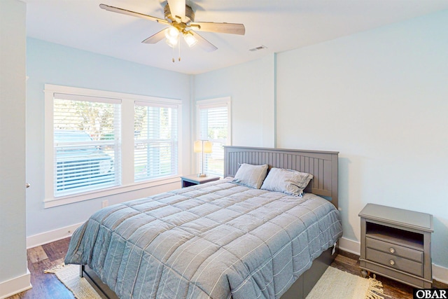 bedroom featuring a ceiling fan, wood finished floors, visible vents, and baseboards