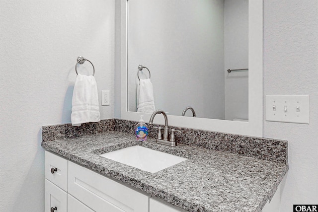 bathroom with a textured wall and vanity