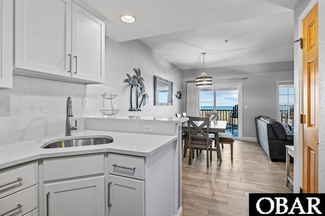 kitchen with plenty of natural light, a sink, white cabinetry, and decorative light fixtures