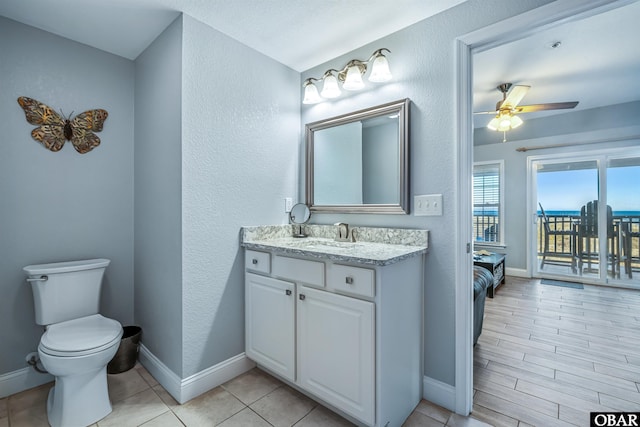 bathroom with baseboards, ceiling fan, vanity, and toilet