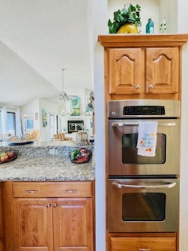 290 Hillcrest Dr Lot 22, Southern Shores, NC 27949 - kitchen with a ceiling fan, light stone counters, lofted ceiling, brown cabinets, and stainless steel double oven