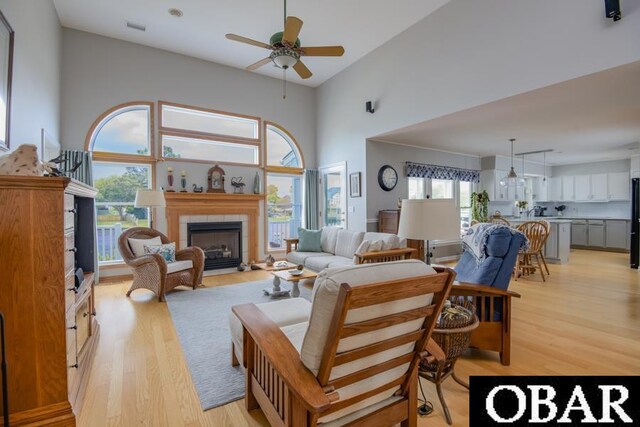 4025 Ivy Ln Lot 11, Kitty Hawk, NC 27949 - living room featuring light wood-style floors, a ceiling fan, a high ceiling, and a fireplace