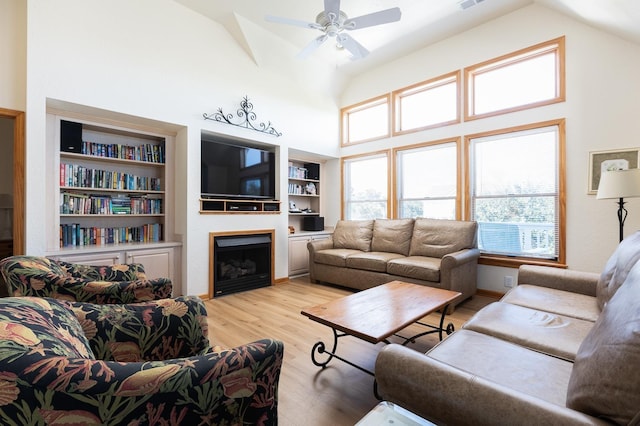 living area featuring light wood-style flooring, a fireplace, high vaulted ceiling, and visible vents