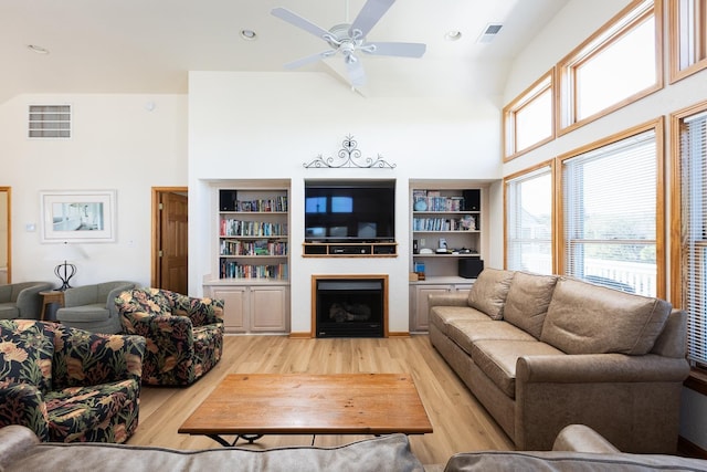 living area with ceiling fan, light wood-type flooring, a fireplace, and visible vents