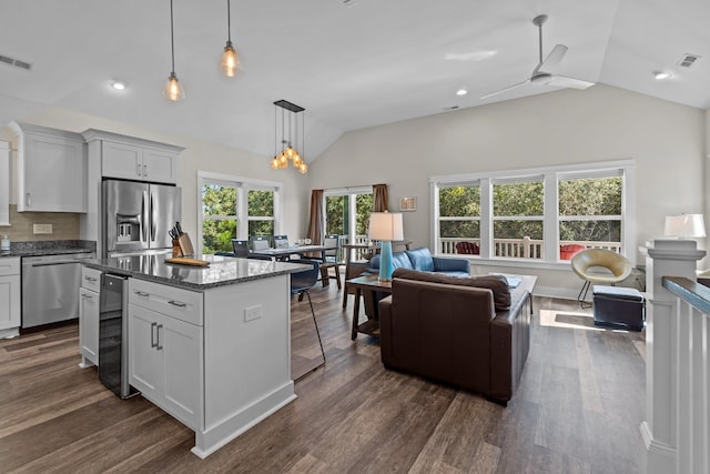 kitchen with lofted ceiling, beverage cooler, appliances with stainless steel finishes, and dark wood-style floors