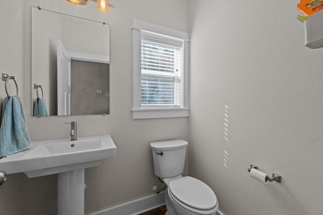 bathroom with toilet, baseboards, and a sink