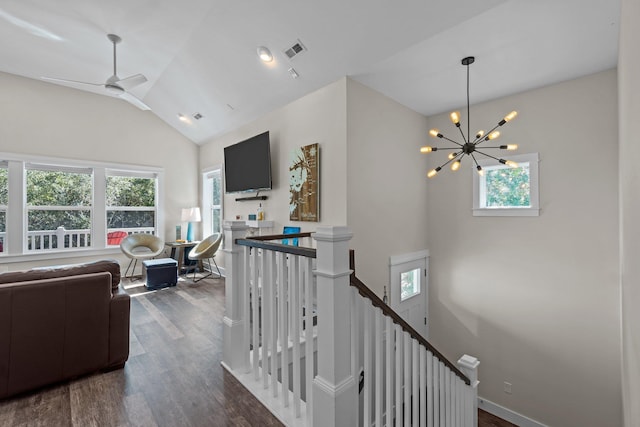 living room featuring lofted ceiling, ceiling fan with notable chandelier, visible vents, baseboards, and dark wood finished floors