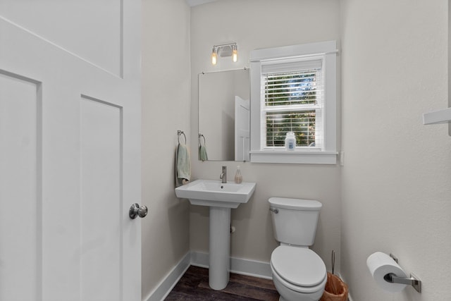 bathroom featuring a sink, toilet, baseboards, and wood finished floors