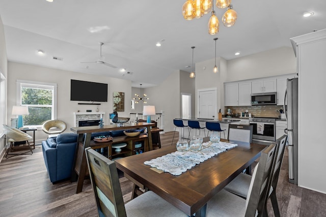 dining room featuring recessed lighting, ceiling fan with notable chandelier, a fireplace, visible vents, and dark wood-style floors