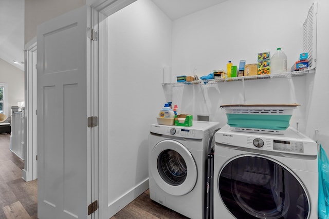 washroom with laundry area, washing machine and dryer, baseboards, and wood finished floors