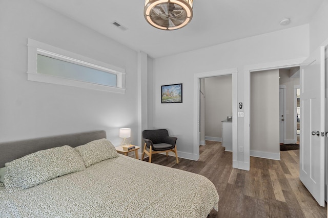 bedroom with dark wood-style flooring, visible vents, and baseboards