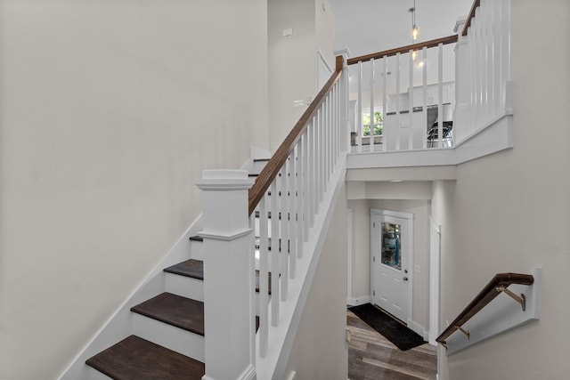 stairway featuring a towering ceiling and wood finished floors