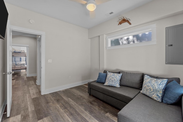 living area featuring electric panel, baseboards, visible vents, a ceiling fan, and wood finished floors