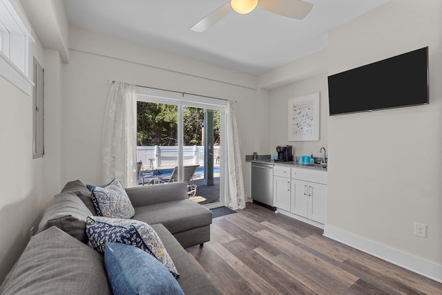 living room with ceiling fan, dark wood-type flooring, indoor wet bar, and baseboards