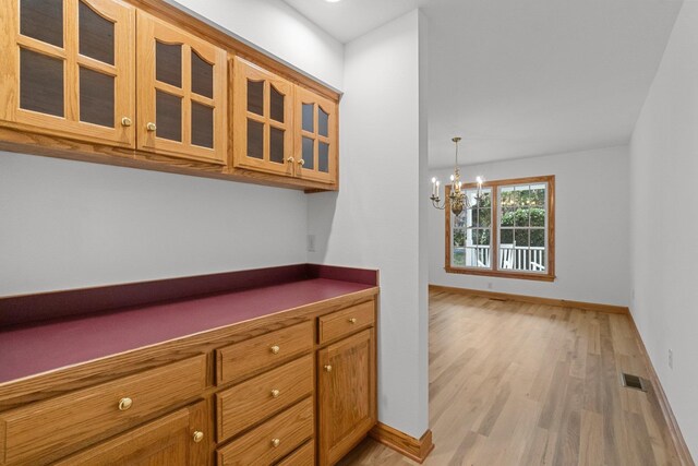 136 Daphne Ln Lot 15, Manteo, NC 27954 - kitchen with light wood-style floors, dark countertops, glass insert cabinets, brown cabinets, and baseboards