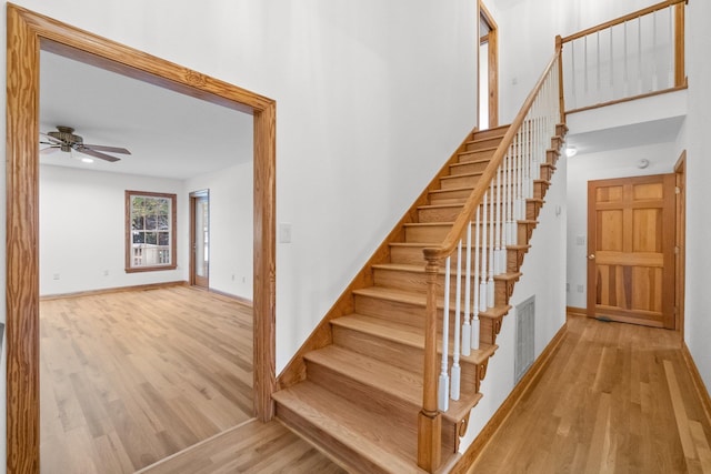 stairs with a ceiling fan, visible vents, baseboards, and wood finished floors