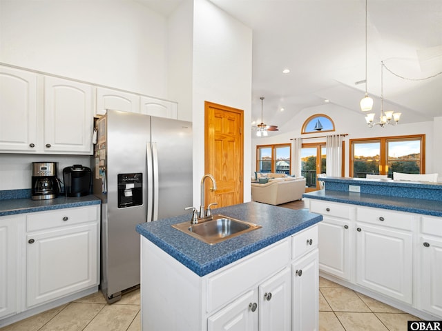 kitchen with dark countertops, a kitchen island, stainless steel refrigerator with ice dispenser, and a sink