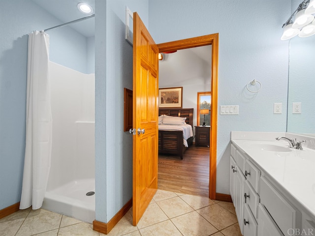 full bath featuring tile patterned flooring, connected bathroom, vanity, baseboards, and a stall shower