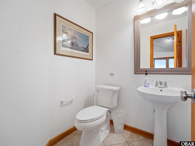 half bath featuring baseboards, a sink, toilet, and tile patterned floors