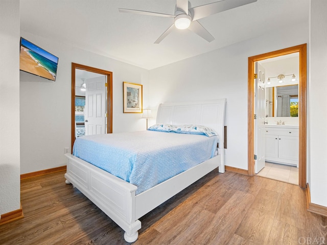 bedroom featuring multiple windows, connected bathroom, baseboards, and wood finished floors