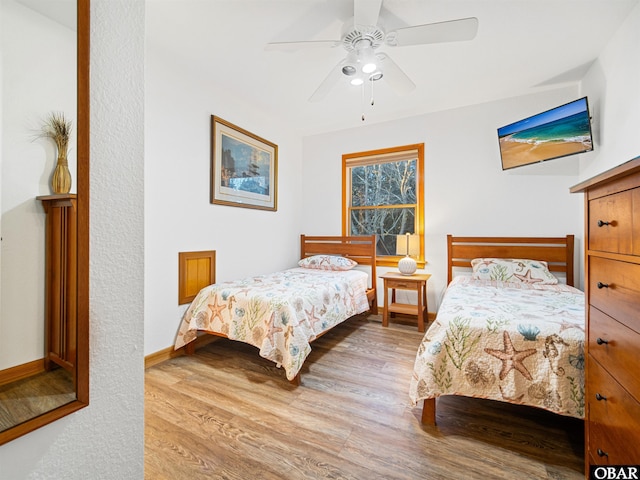 bedroom featuring ceiling fan, baseboards, and wood finished floors