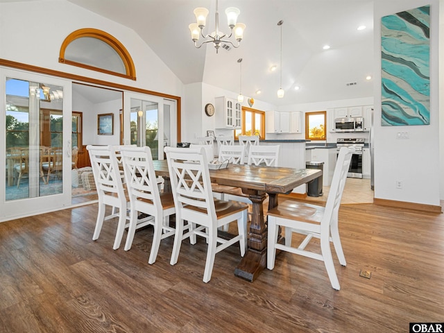 dining space featuring a notable chandelier, vaulted ceiling, wood finished floors, and recessed lighting