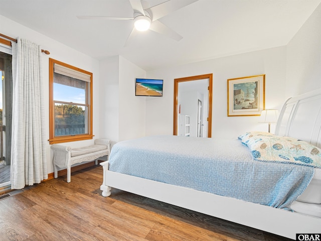 bedroom featuring a ceiling fan, visible vents, and wood finished floors