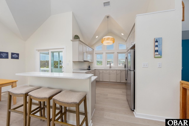 25245 Island Pines Dr Lot 6, Waves, NC 27982 - kitchen featuring black electric stovetop, white microwave, freestanding refrigerator, a breakfast bar area, and visible vents