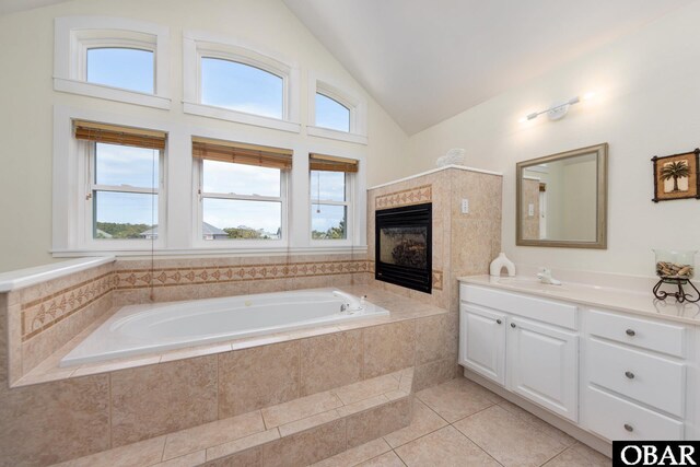 25245 Island Pines Dr Lot 6, Waves, NC 27982 - bathroom featuring tile patterned flooring, a garden tub, vanity, high vaulted ceiling, and a tile fireplace