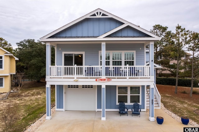 coastal home featuring board and batten siding, covered porch, driveway, and an attached garage