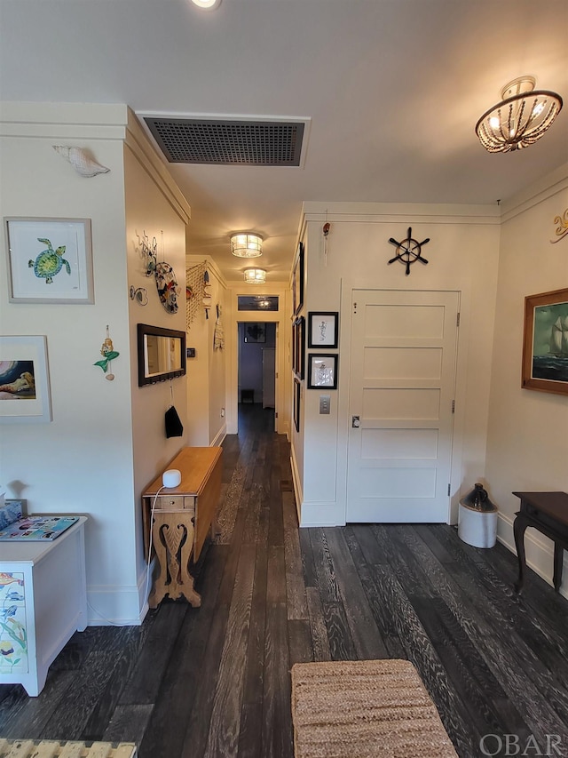 hallway featuring baseboards, crown molding, visible vents, and dark wood-style flooring