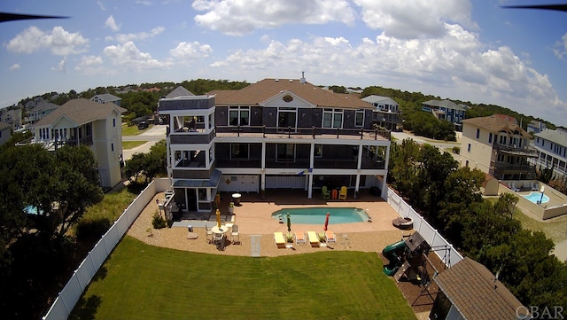 back of property with a lawn, a patio area, a fenced backyard, and a fenced in pool