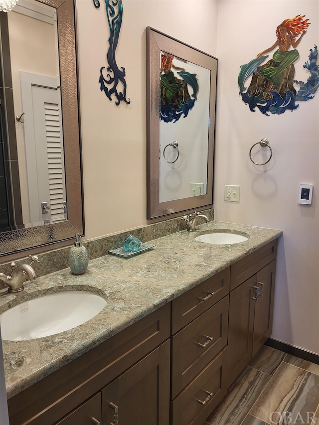 bathroom featuring double vanity, a sink, and baseboards